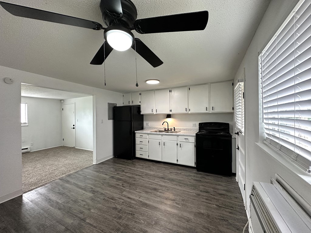 an empty kitchen and living room with a ceiling fan