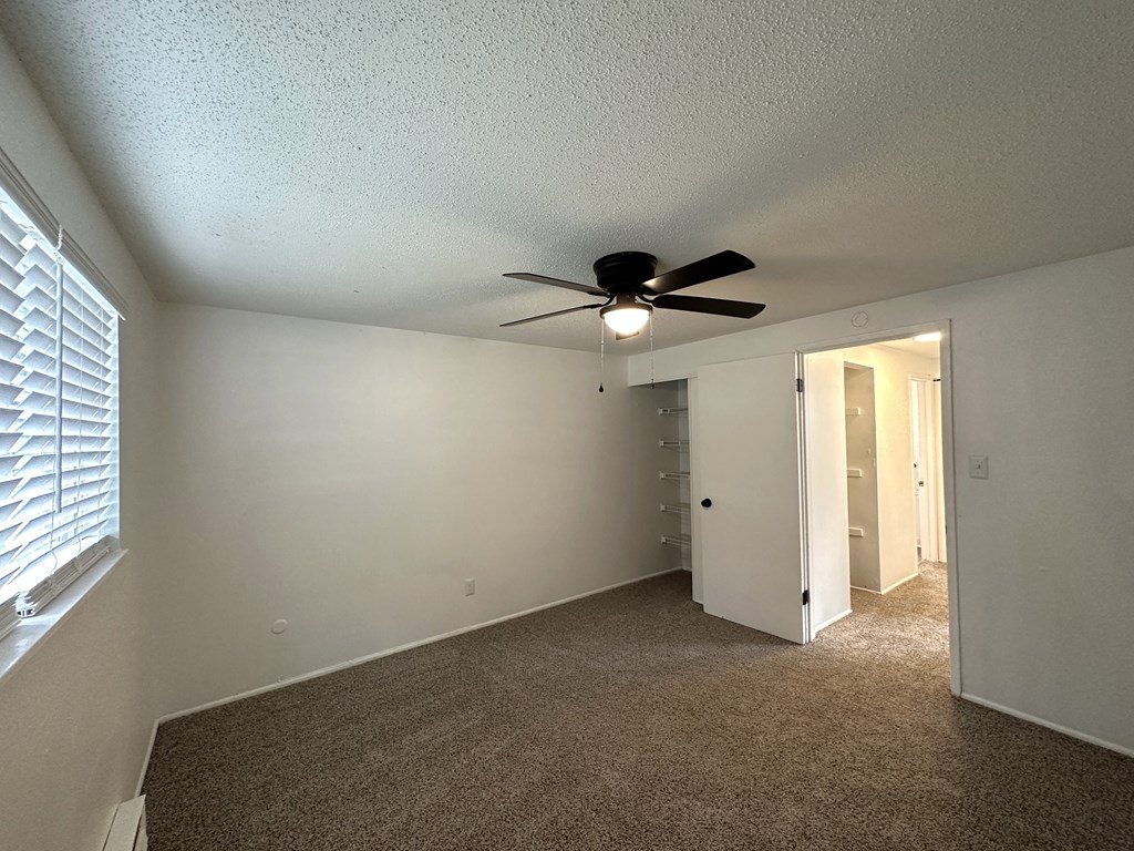 an empty bedroom with a ceiling fan