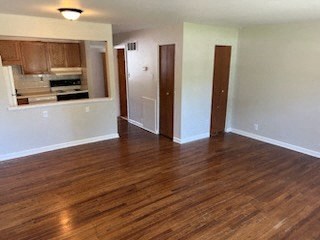a living room with a wooden floor and a kitchen in the background