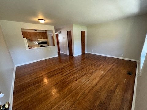 a living room with a wooden floor and a kitchen in the background