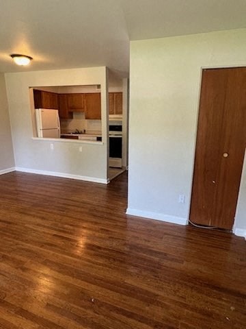 a living room with a wooden floor and a kitchen in the background