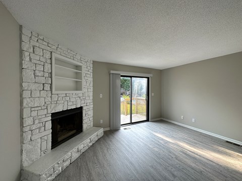 an empty living room with a stone fireplace