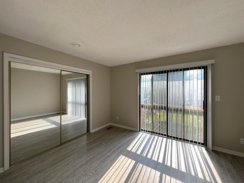 an empty bedroom with a sliding glass door and a mirrored closet