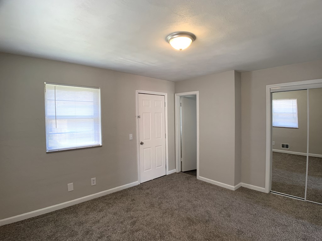 Room with mirrored closet and window