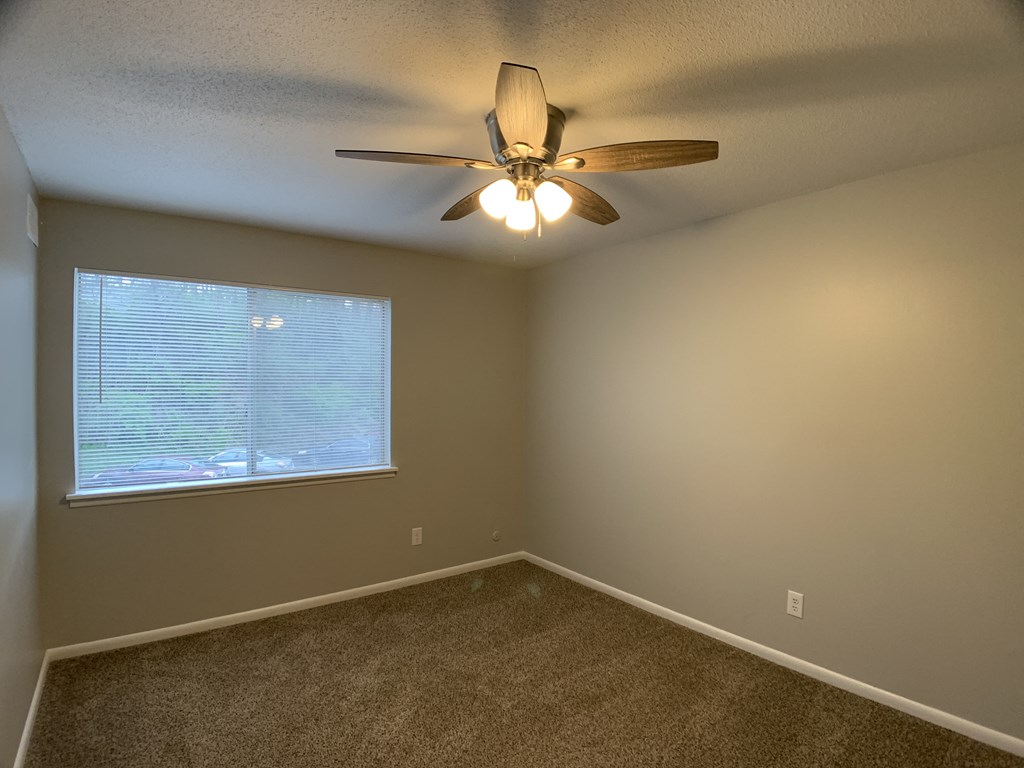 carpeted bedroom with ceiling fan and medium sized window