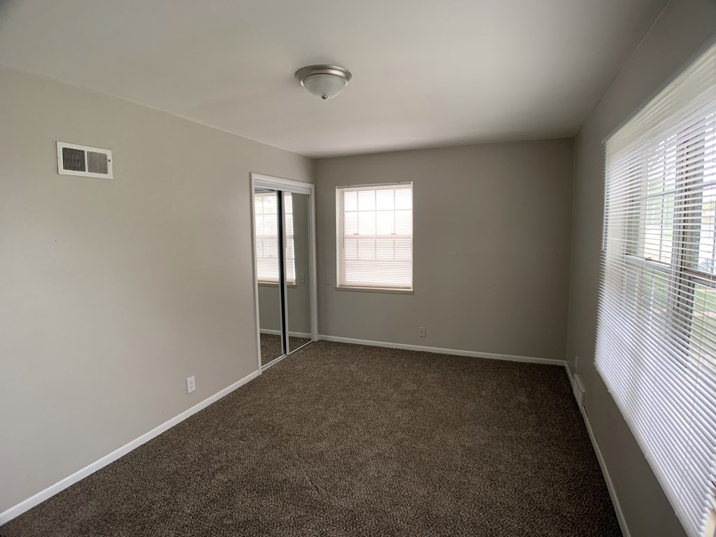 Spacious bed room with mirrored closets and 2 windows