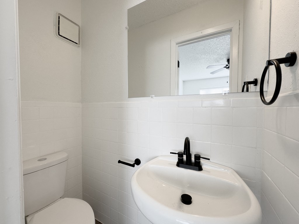 A white bathroom with a toilet, sink and mirror.