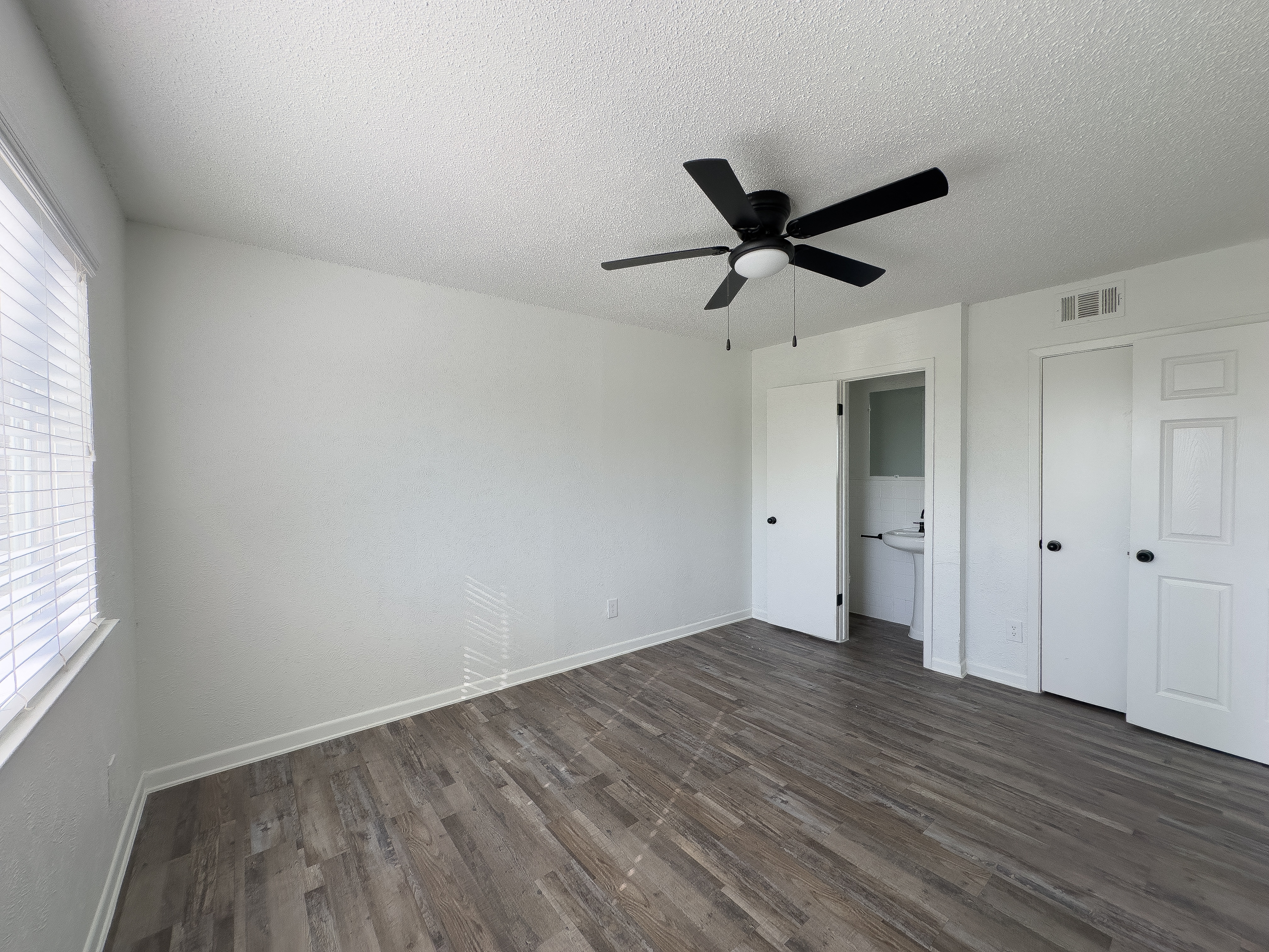 A room with a ceiling fan and wooden flooring.