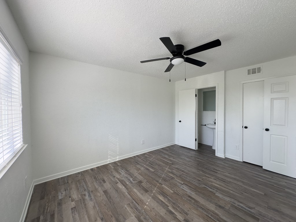 an empty living room with white walls and a ceiling fan