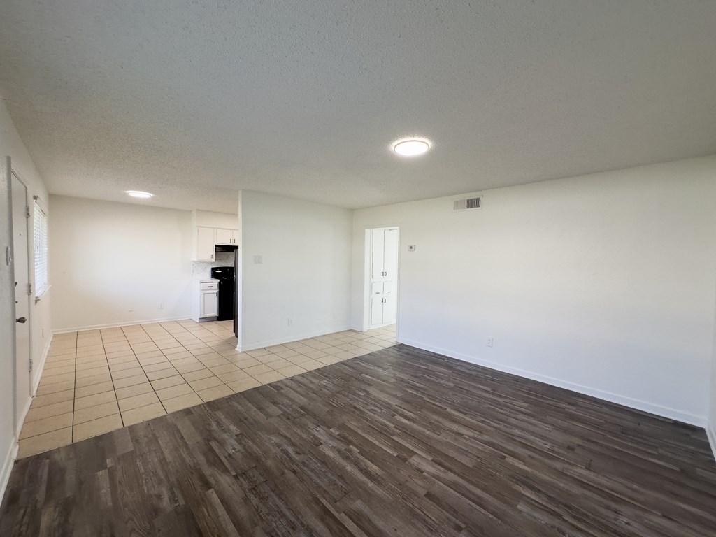 an empty living room with white walls and wood flooring
