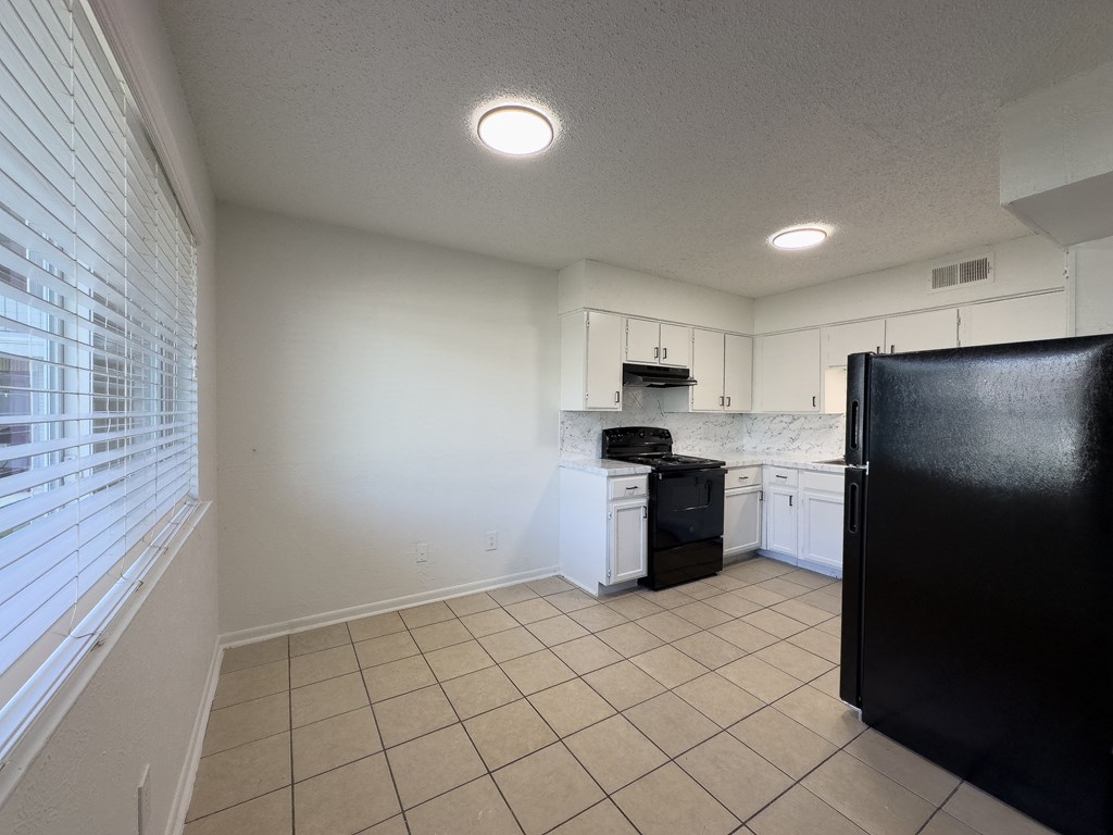A kitchen with black appliances and white cabinets.