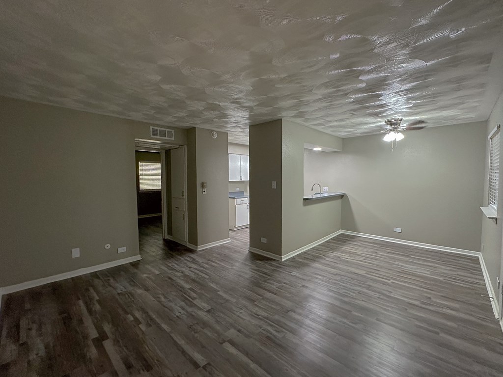 an empty living room with a hard wood floor and grey walls