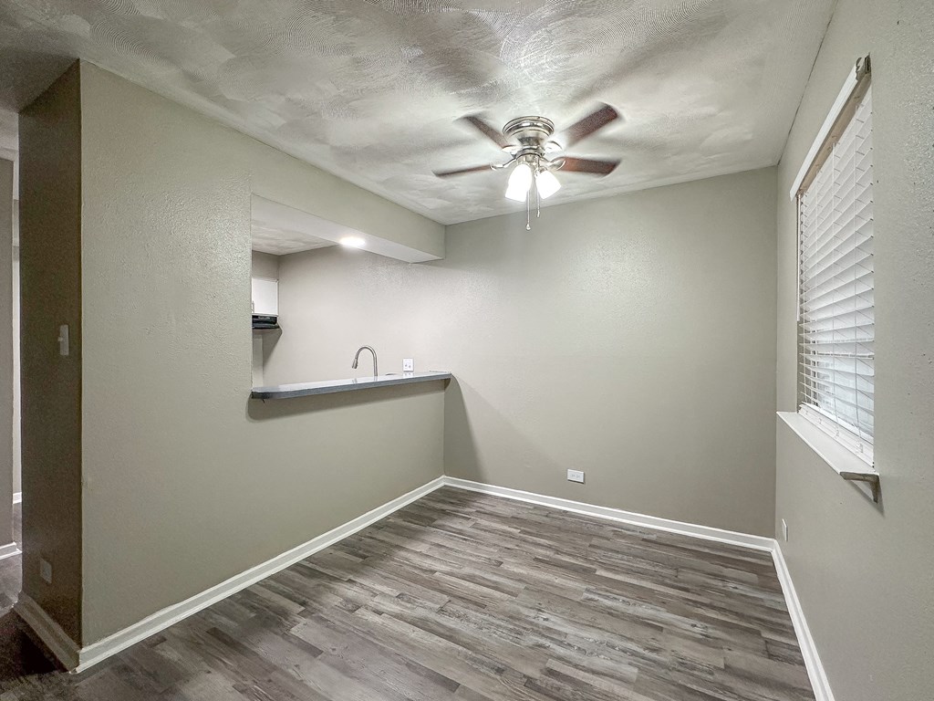 an empty living room with a ceiling fan and a window