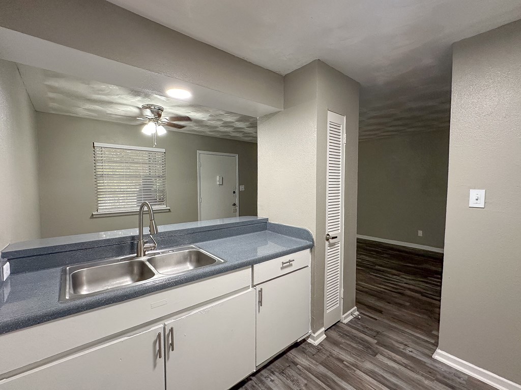 an empty kitchen with a sink and a ceiling fan