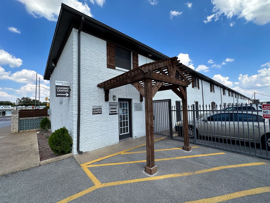 a white building with a wooden structure in front of a parking lot