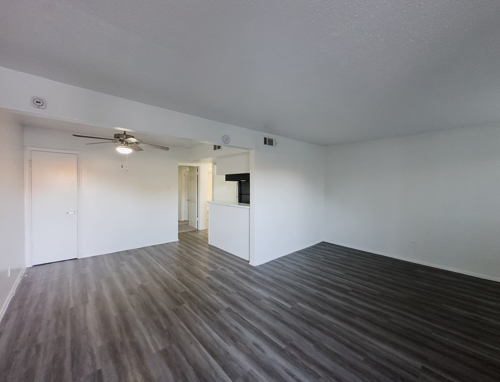 A room with a ceiling fan and wooden flooring.