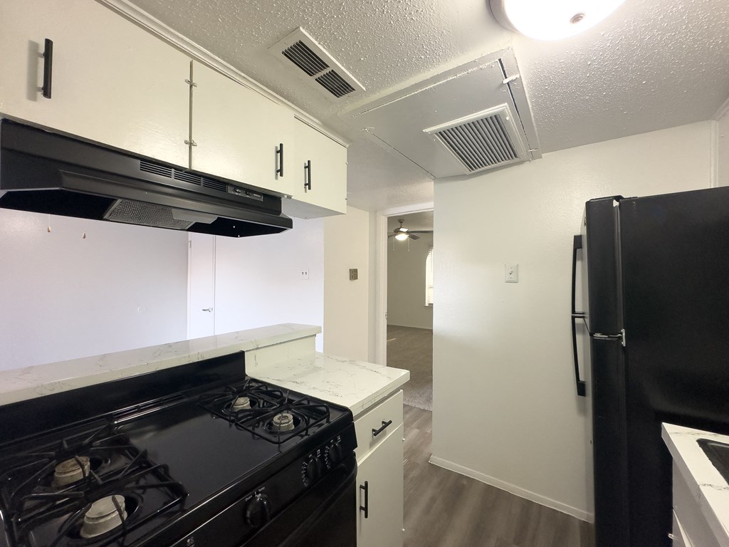 A kitchen with black appliances and white cabinets.