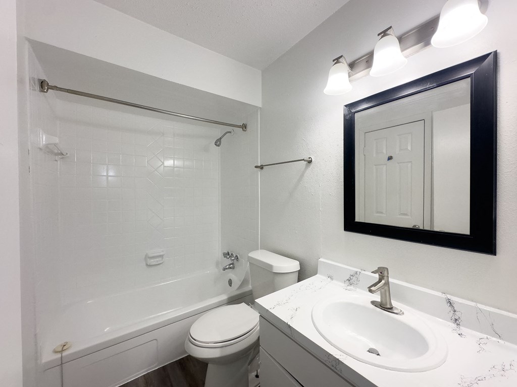 A white bathroom with a toilet, sink, and shower.