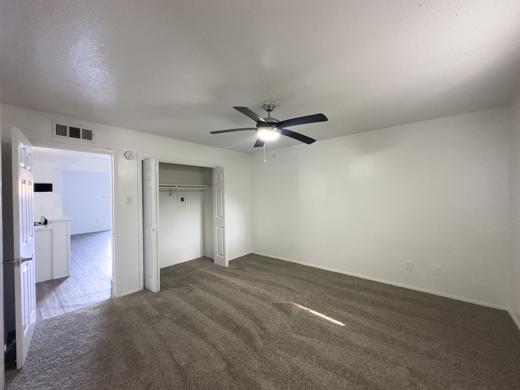A room with a ceiling fan and carpeted floor.