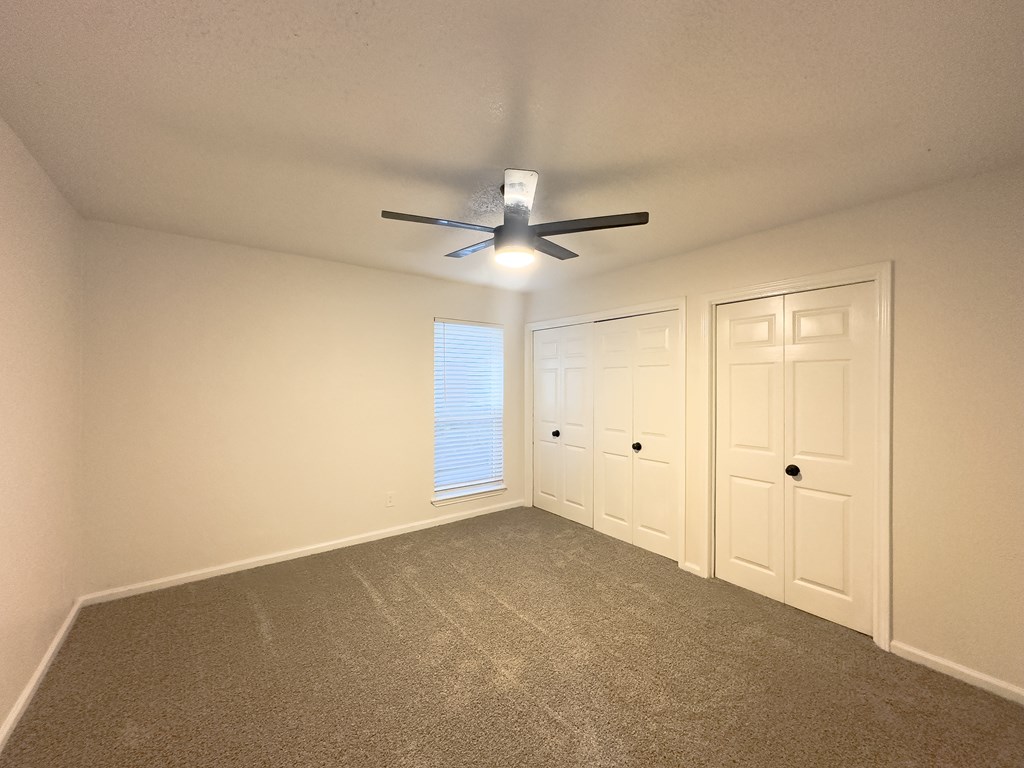 A room with a ceiling fan and two doors.