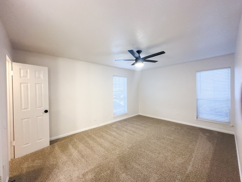 A room with a ceiling fan and carpeted floor.