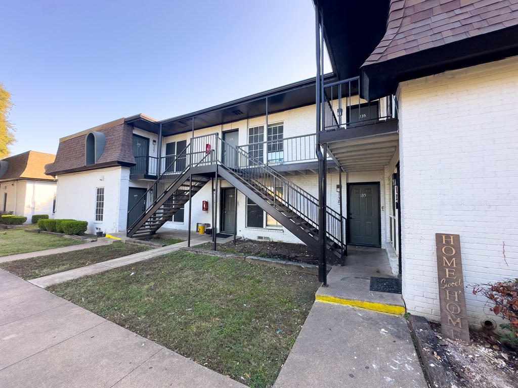 A white building with a black railing and a sign that says Home.