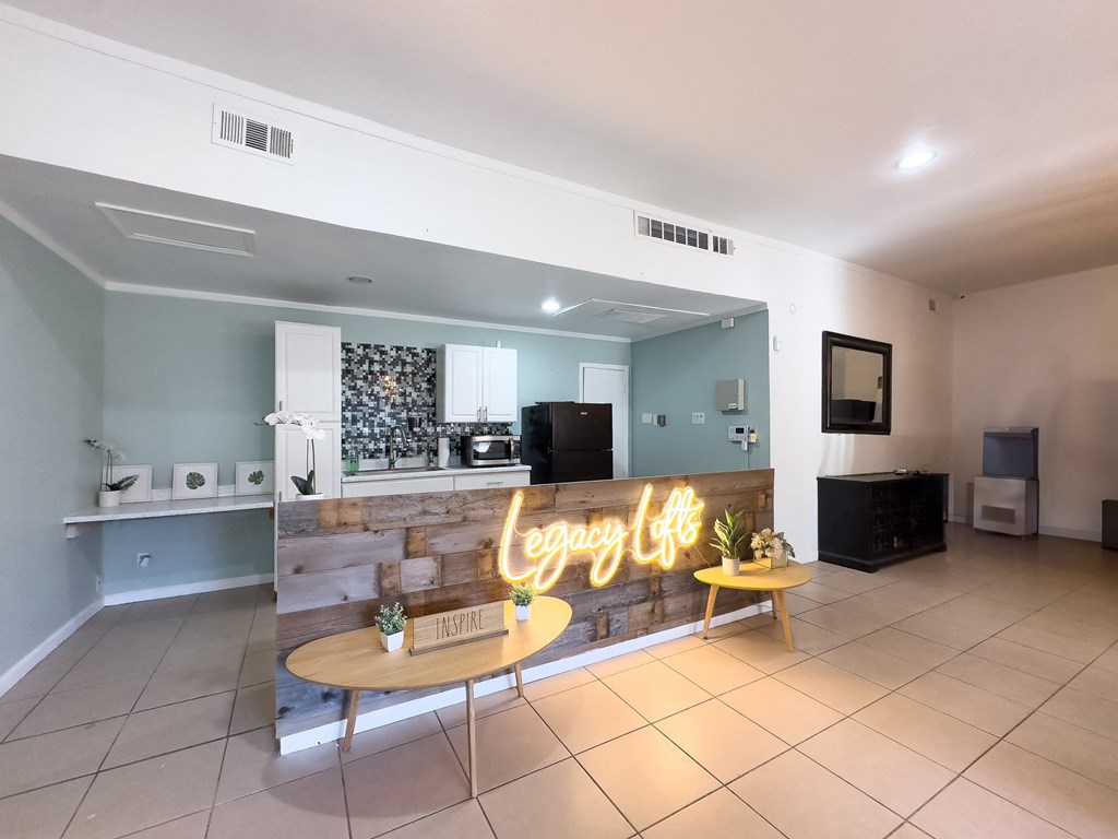 A room with a neon sign that says "Legacy Lift" and a table with a plant on it.