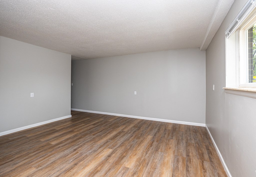 an empty bedroom with hardwood floors and a large window