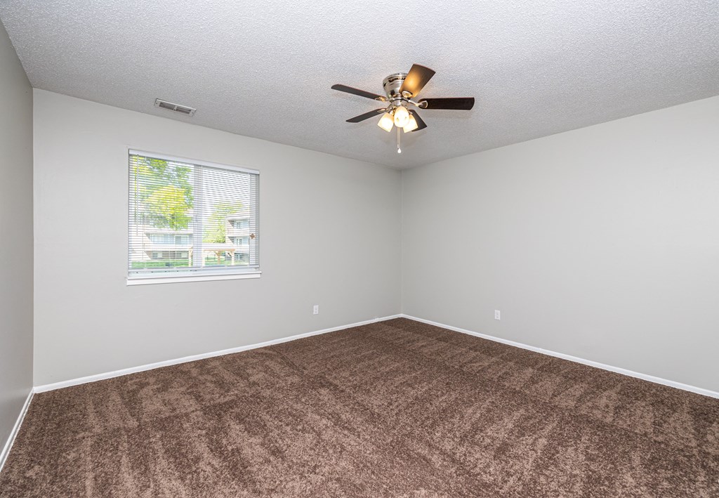 an empty room with a ceiling fan and a window