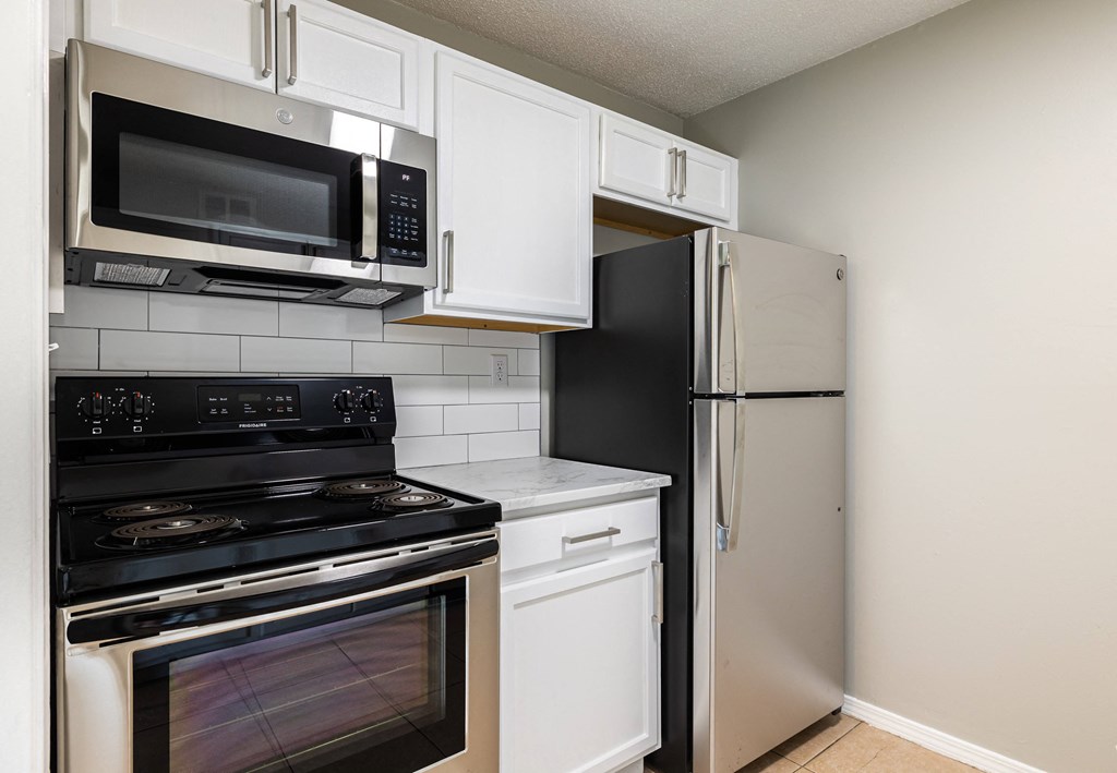 a kitchen with white cabinets and stainless steel appliances
