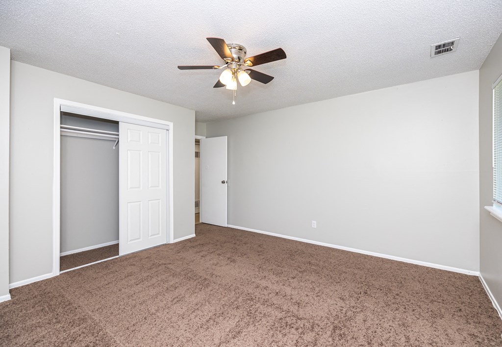 a bedroom with a ceiling fan and a closet