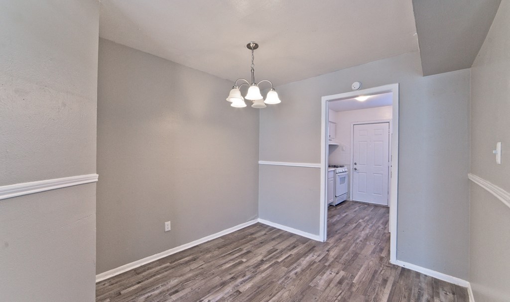 an empty living room with wood flooring and a door to a bathroom