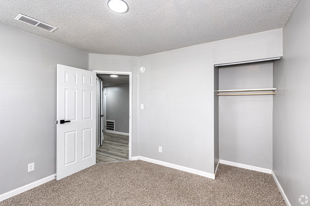 an empty bedroom with a closet and a door to a hallway
