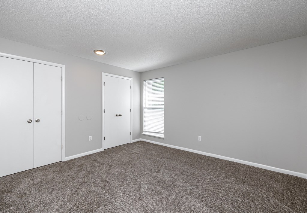 a bedroom with a carpeted floor and a door to a closet