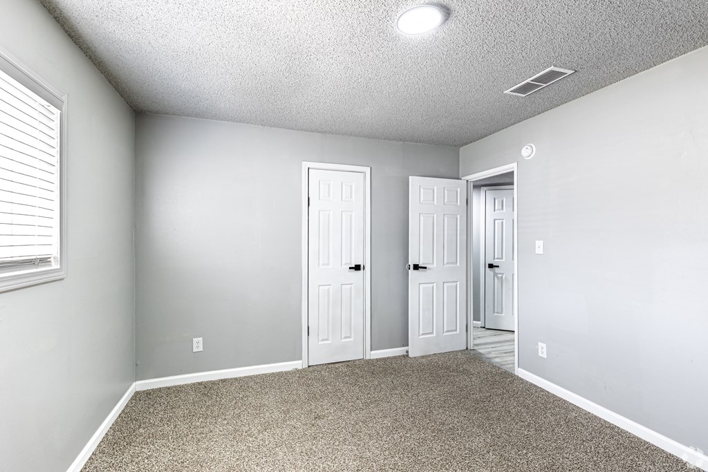 an empty room with two doors and a carpeted floor