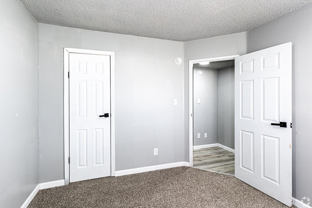 an empty room with two doors and a door open to a closet