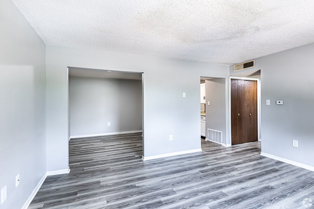 an empty living room with wood floors and white walls