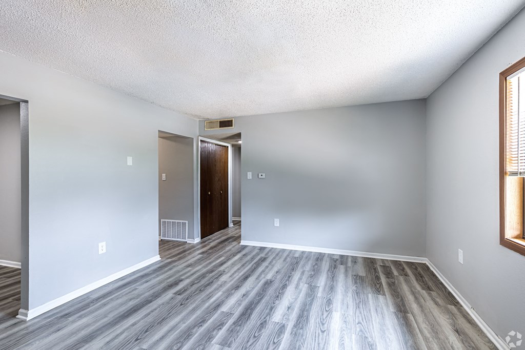 an empty living room with wood flooring and white walls