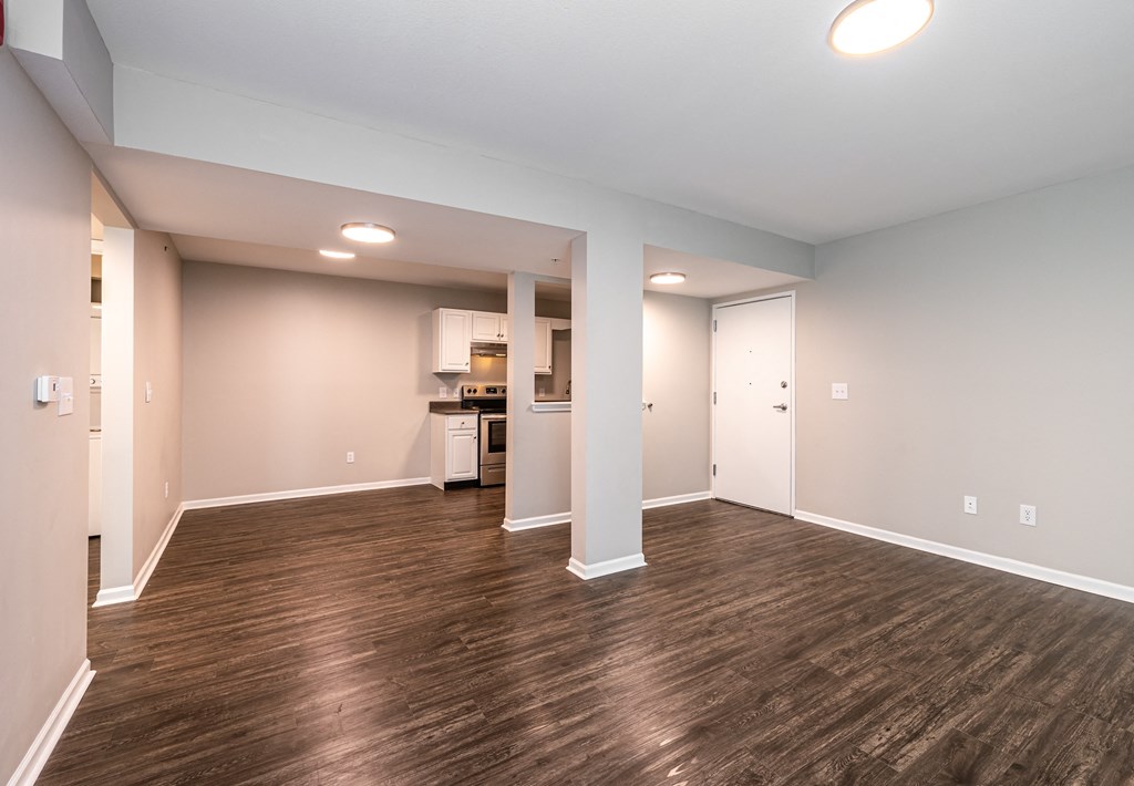 a living room with a hardwood floor and a kitchen in the background