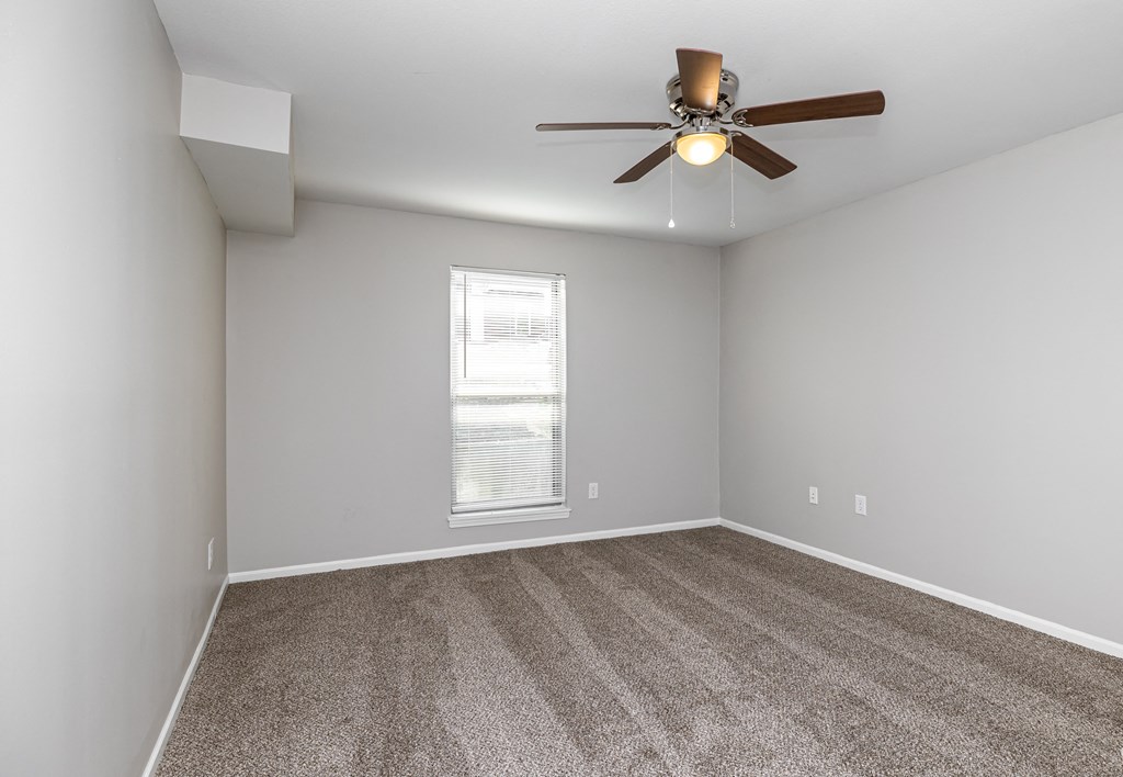 an empty room with a ceiling fan and a window