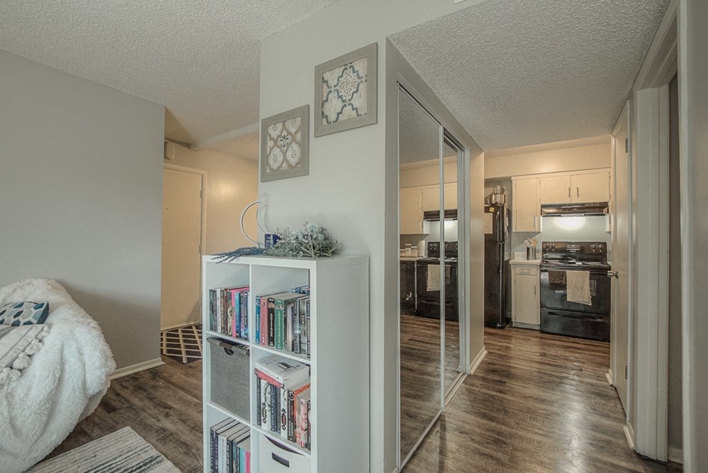 Photo of furnished room with kitchen to the right and hallway to the left.