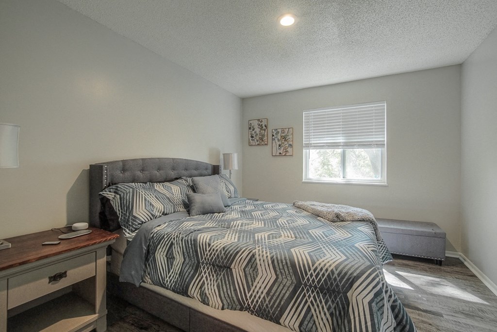 Photo of bedroom with bed and window facing the sun.