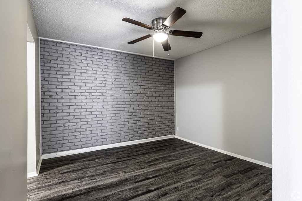 Photo of room with vinyl flooring, stone accent wall and ceiling fan.