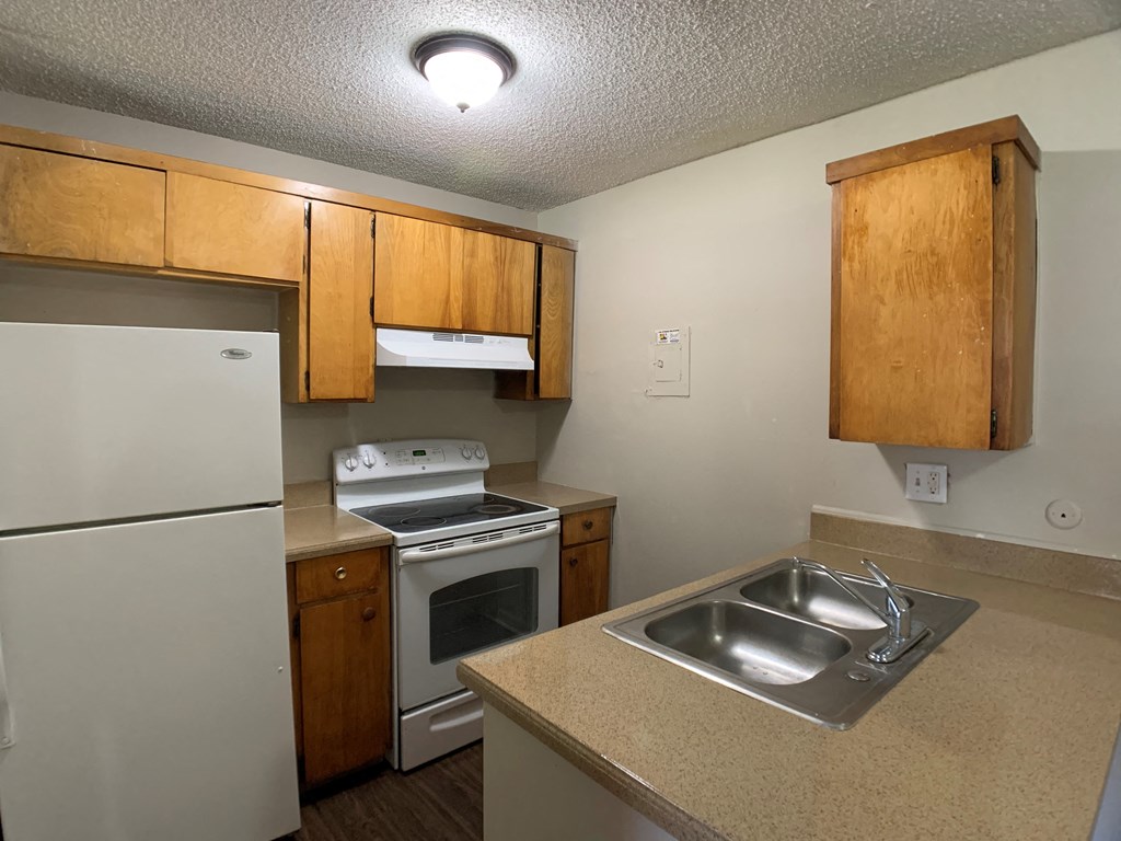 Image of a kitchen with a breakfast bar, refrigerator, sink, and oven.