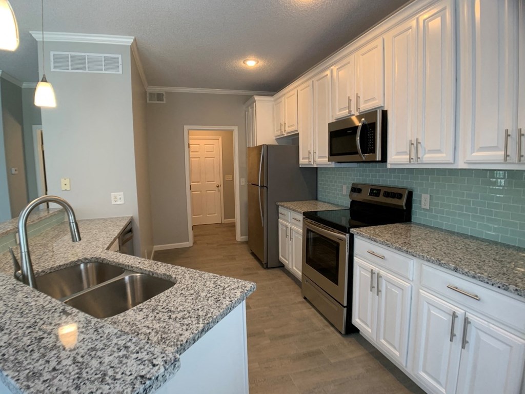 a kitchen with granite counter tops and white cabinets