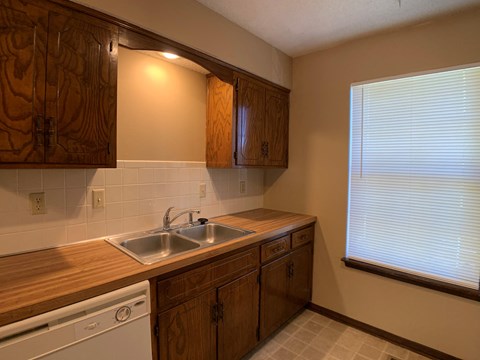 A kitchen with wooden cabinets and a white dishwasher.