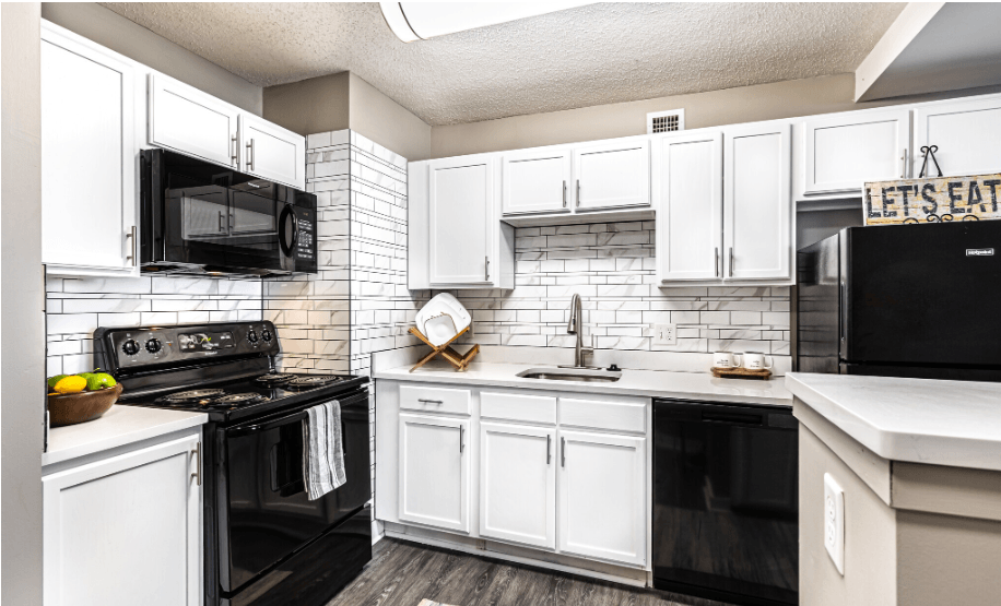 a white kitchen with black appliances and white cabinets
