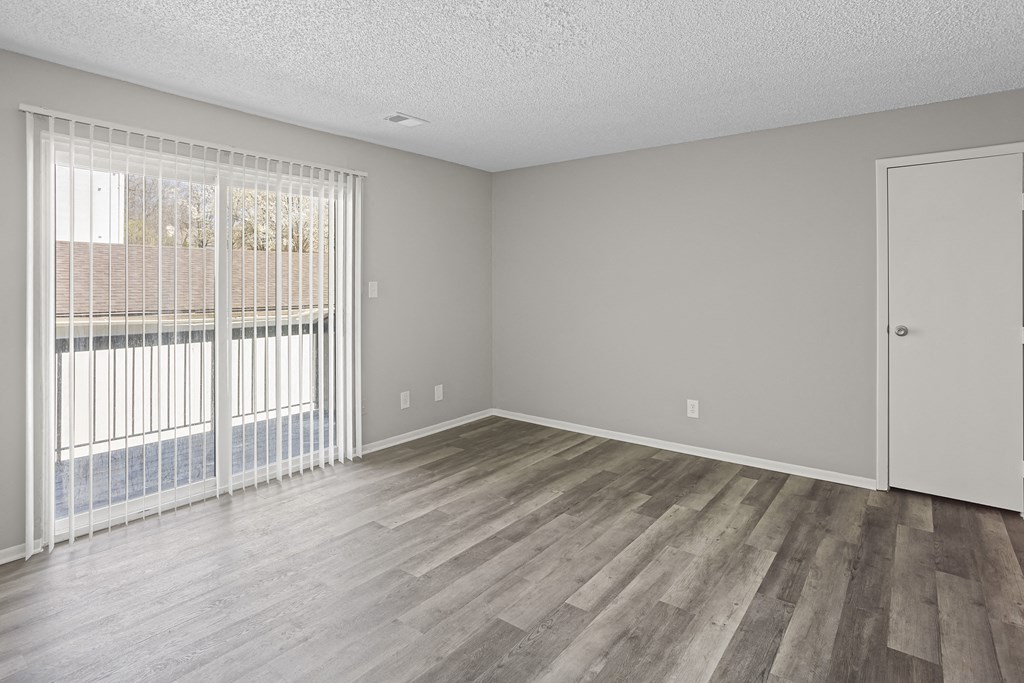 an empty living room with wood flooring and a large window
