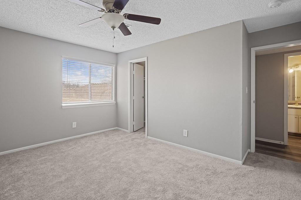 an empty living room with a ceiling fan and a window