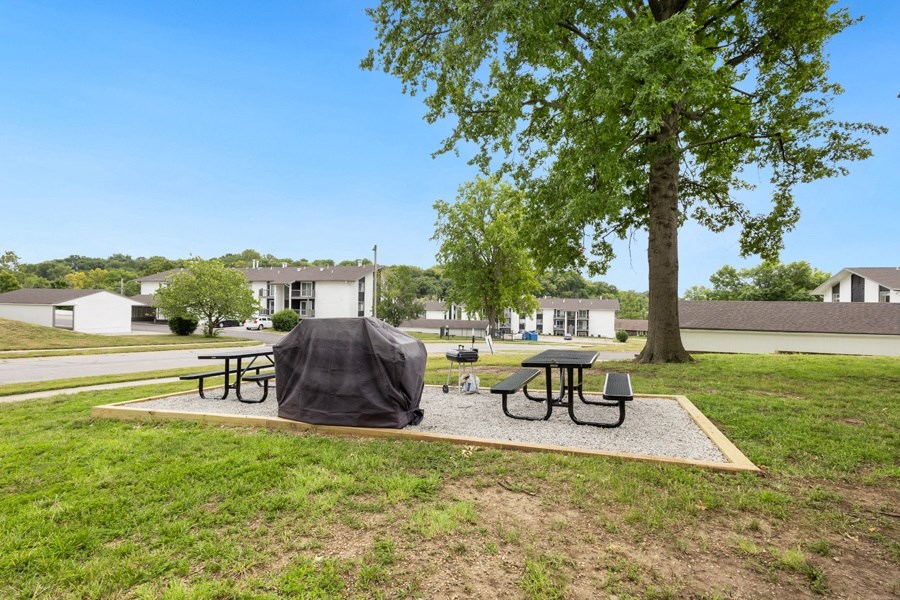a picnic area with picnic tables and a tent in a park